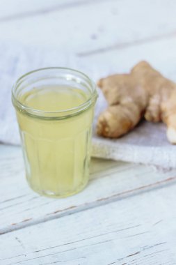 Arkasında zencefil kökü olan küçük cam kavanozda zencefil suyu..