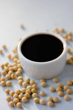 Beyaz arka planda soya fasulyeleriyle çevrili soya fasulyesi sosu..