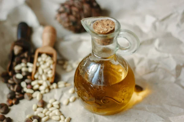 Glass bottle filled by cedar or pine oil surrounded by pine nuts.