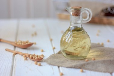 Etrafında soya fasulyesi olan cam şişedeki soya fasulyesi yağı..