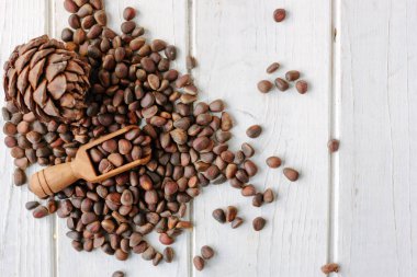 Beyaz ahşap zemin üzerinde tahta bir kaşık çam fıstığı Üstten Görünüm.