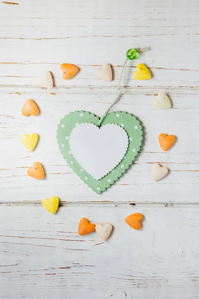 Corazón verde en círculo de pequeños corazones anaranjados y amarillos sobre fondo de madera . — Foto de Stock