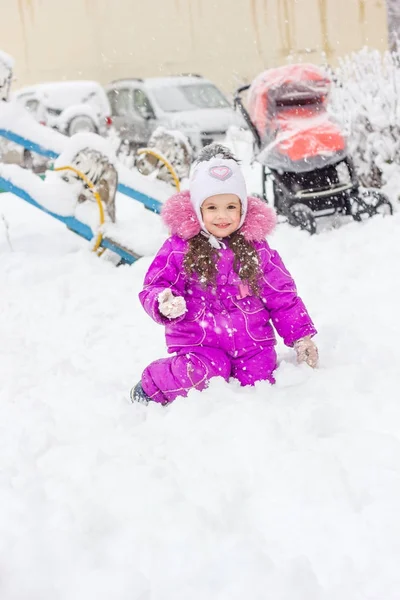 Petite fille jouant dans une aire de jeux enneigée en hiver — Photo