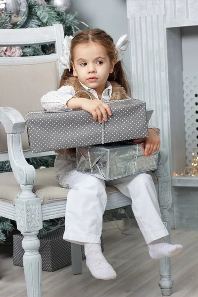 Petite fille assise sur une chaise avec boîte cadeau de Noël . — Photo