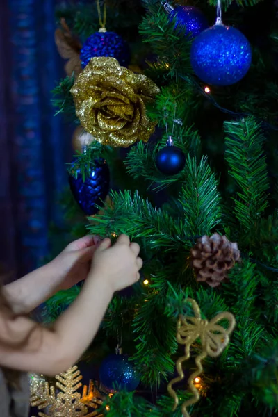 Mains de petite fille décorant l'arbre de Noël par des boules bleues . — Photo