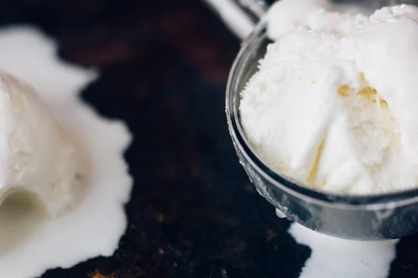 Vista próxima de colher de sorvete com sorvete branco começando a derreter nele . — Fotografia de Stock