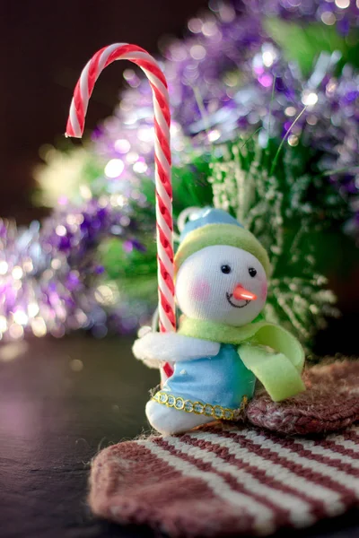 Toy snowman holding christmas candy cane in hands. — Stock Photo, Image