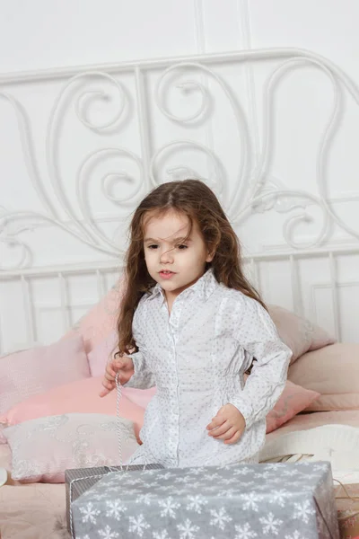 Petite fille assise sur le lit avec les boîtes de cadeaux de Noël . — Photo