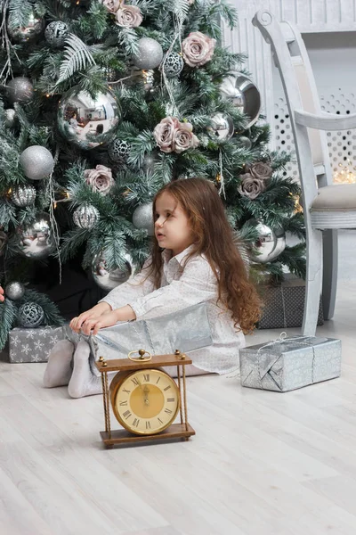 Petite fille avec l'horloge près de l'arbre de Noël . — Photo