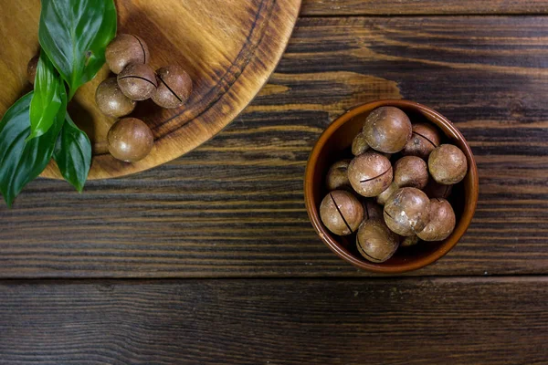 Верхний вид орехов макадамии в коричневой керамической миске на деревянный стол . — стоковое фото