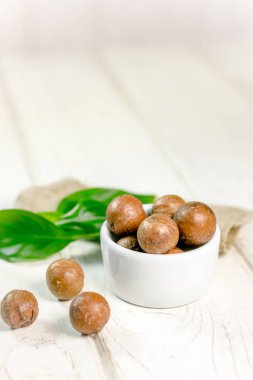 Macadamia fındık ahşap masa üzerinde beyaz seramik kase.