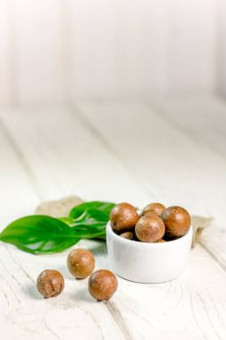 Macadamia fındık ahşap masa üzerinde beyaz seramik kase.
