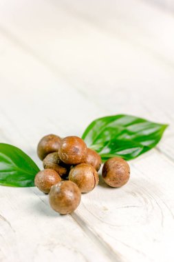 Ahşap masa üzerinde taze ve olgun macadamia fındık.