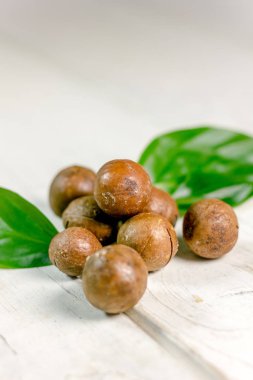 Ahşap masa üzerinde taze ve olgun macadamia fındık.