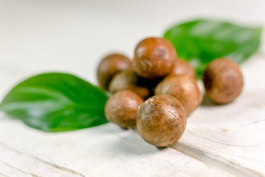 Ahşap masa üzerinde taze ve olgun macadamia fındık.