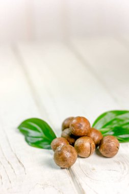 Ahşap masa üzerinde taze ve olgun macadamia fındık.