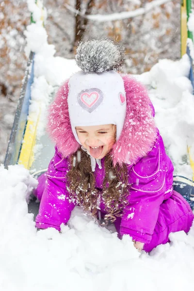 雪の降る冬の日に子供のスライドの子供女の子. — ストック写真