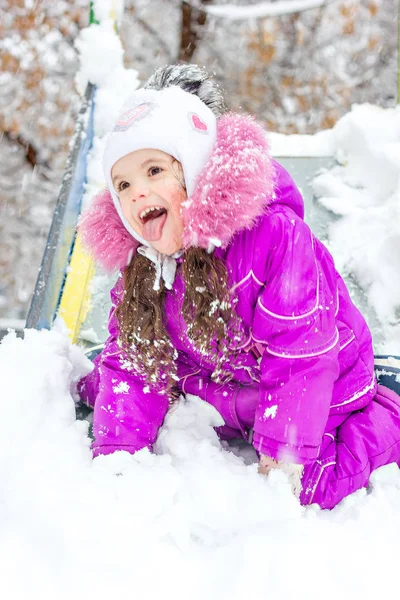 Девочка на детской горке в снежный зимний день . — стоковое фото