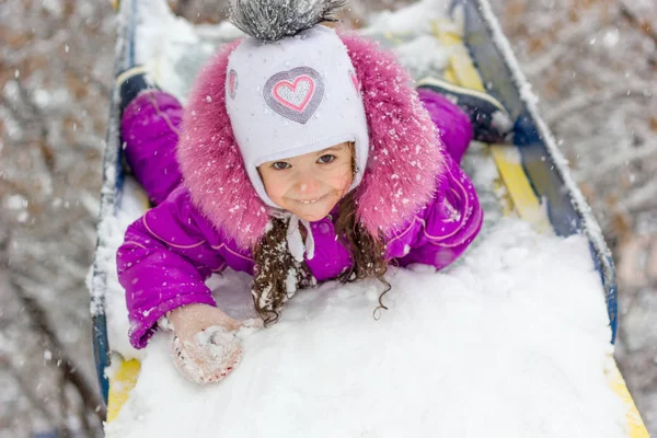 Kız çocuk slayt üzerinde karlı kış gününde evlat..