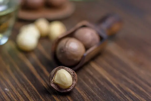Nueces de macadamia en una cucharada de madera sobre la mesa oscura . — Foto de Stock