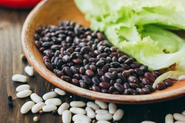 Ahşap tahta üzerinde kahverengi seramik plaka üzerinde siyah fasulye.