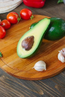 Tahtada diğer sebzelerle birlikte avokado meyvesi var..