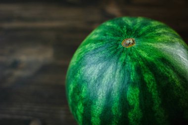 Bölünmemiş karpuzun yakın çekim görüntüsü. Kahverengi ahşap zemin üzerinde yeşil taze karpuz.