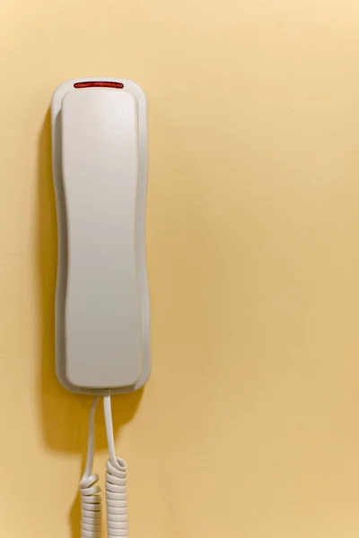 Teléfono de plástico blanco en una pared para llamadas de emergencia o soporte. — Foto de Stock