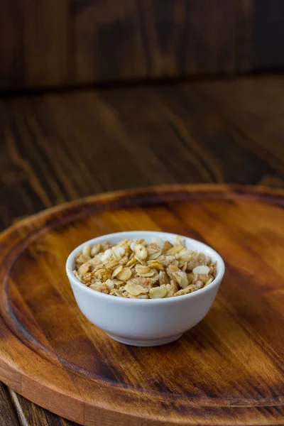 Granola lub musli w białej ceramicznej misce nad drewnianym stołem. — Zdjęcie stockowe