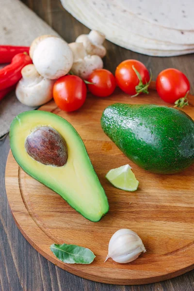 Avocadofrucht auf Holzbrett mit anderem Gemüse. — Stockfoto