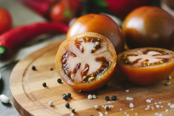 Tomatenhälften auf Holzbrett, umgeben von Gemüse und Gewürzen. — Stockfoto