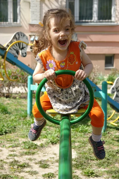 Garotinha se divertindo no playground no dia ensolarado da primavera — Fotografia de Stock