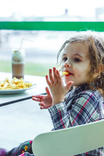 Niña en un restaurante comiendo comida rápida. — Foto de Stock