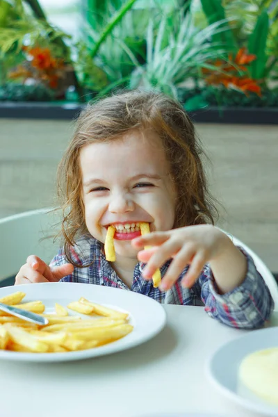 Niña jugando con las papas fritas en un restaurante . — Foto de Stock