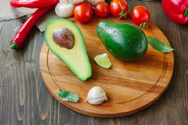 Avocadofrucht auf Holzbrett mit anderem Gemüse. — Stockfoto