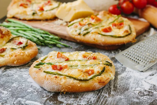 Mini pizza with asparagus. Traditional small pizza for personal eating filling with cheese, tomatoes and asparagus.