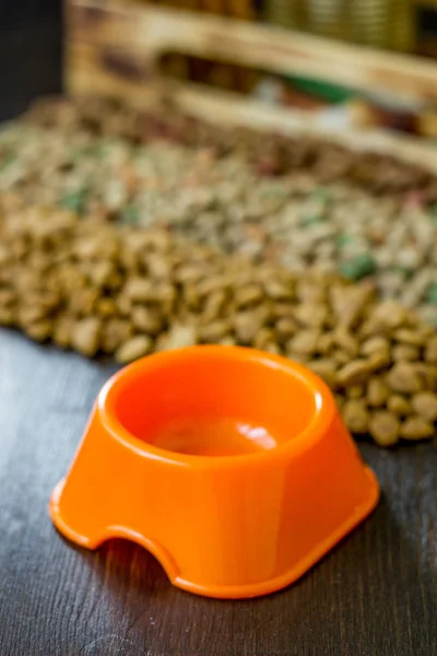 Маленькая оранжевая миска для корма для домашних животных и сухой пищи в качестве фона. — стоковое фото