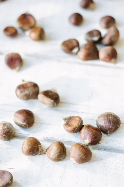 Castagne fresche crude su superficie di legno bianca. — Foto Stock