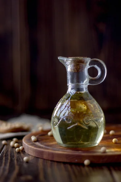 Soy bean oil in glass bottle with soybeans around it.