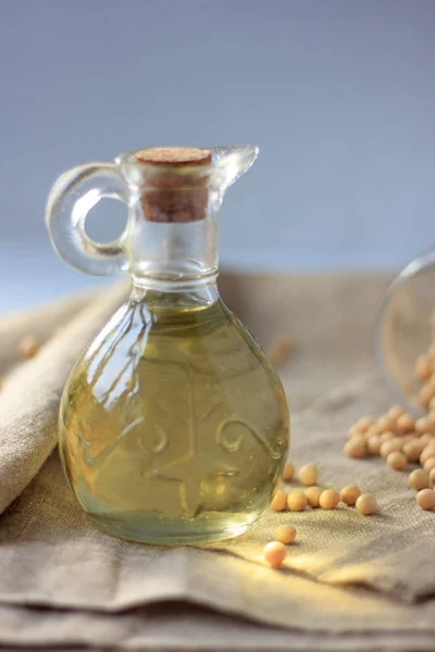 Soy bean oil in glass bottle with soybeans around it.