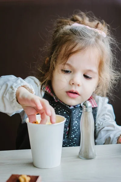 Niña comiendo papas fritas en el restaurante. — Foto de Stock