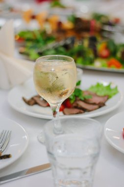 Restoran masasında beyaz şarapla dolu bir bardak..