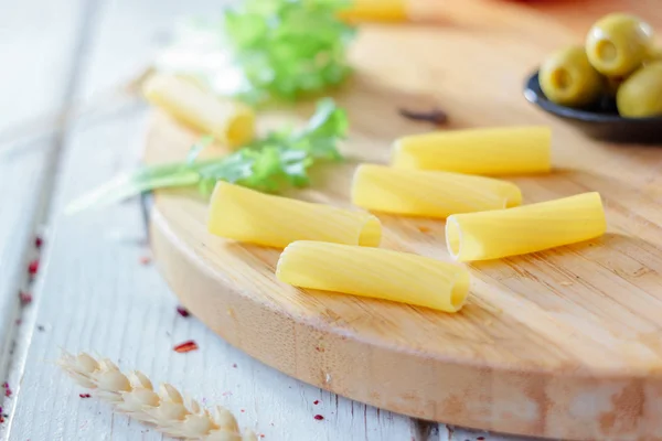 Pastas italianas de tortiglioni listas para cocinar en el tablero de la cocina. —  Fotos de Stock