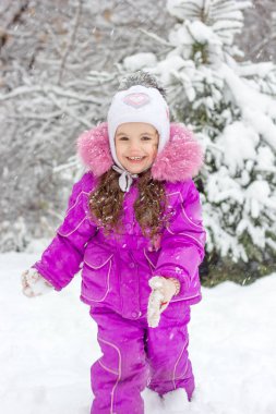 Küçük kız karlı kış günü açık havada üzerinde eğleniyor