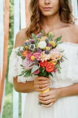 Güzel gelin düğün çiçek buketi açık havada elinde tutan