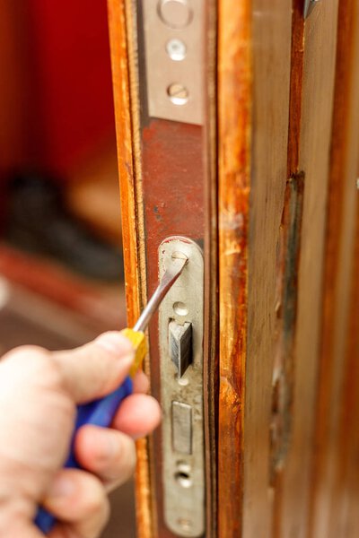 Locksmith making installation of door lock with screwdriver