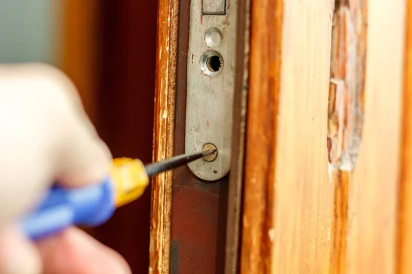 Locksmith making installation of door lock with screwdriver