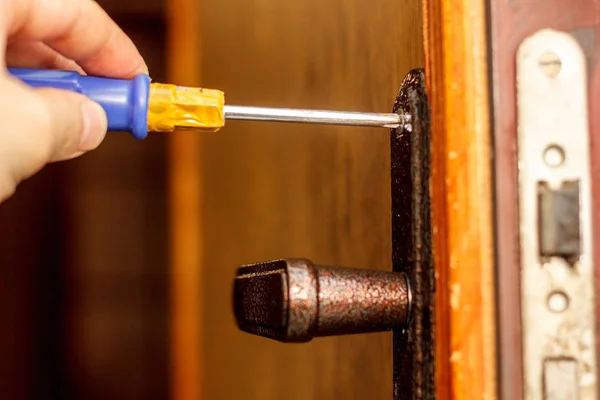 Locksmith making installation of door lock with screwdriver