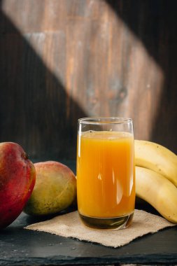 Cam siyah yüzey üzerinde muz ve mango suyu ile dolu