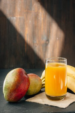Cam siyah yüzey üzerinde muz ve mango suyu ile dolu
